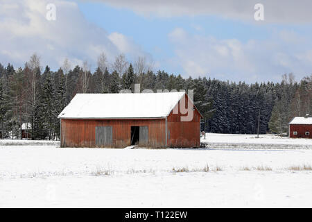 Paysage rural avec grange en bois rouge en champ neigeux sur une belle journée d'hiver. Banque D'Images