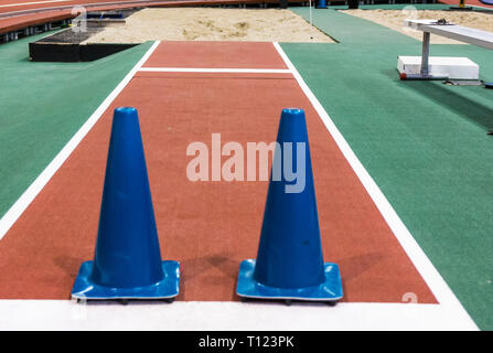 Deux grands cônes bleus sont mis en place sur une longue piste jumpr pour bloquer les athlètes de saut dans le sable. Banque D'Images