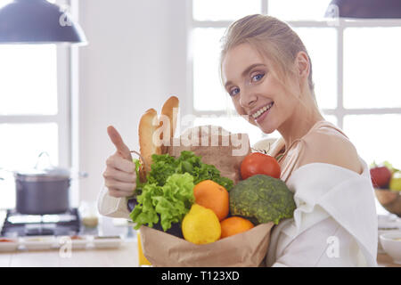 Jeune femme tenant un sac d'épicerie avec des légumes Standi Banque D'Images