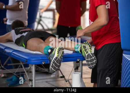 Étendu sur un lit de l'athlète tout en ayant les jambes massées après un entraînement physiques sportives. Banque D'Images