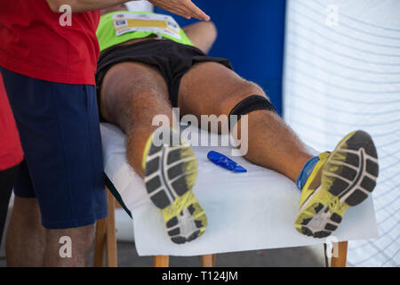 Étendu sur un lit de l'athlète tout en ayant les jambes massées après un entraînement physiques sportives. Banque D'Images