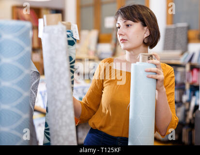 Vendeur féminin organisation d'assortiment de textile sur étagères en tissu boutique Banque D'Images