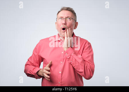 Senior man in red shirt souffrant de douleurs dentaires. Il a besoin d'aller à votre médecin. Banque D'Images