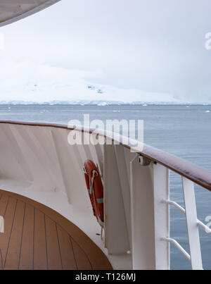 Un équipage de pont en bois, bois et métal main courante et conservateur de vie dans l'avant-plan et d'un glacier en Antarctique dans l'arrière-plan. Banque D'Images