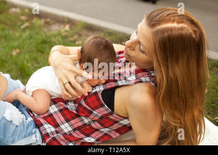 Mother holding newborn baby girl in the park Banque D'Images