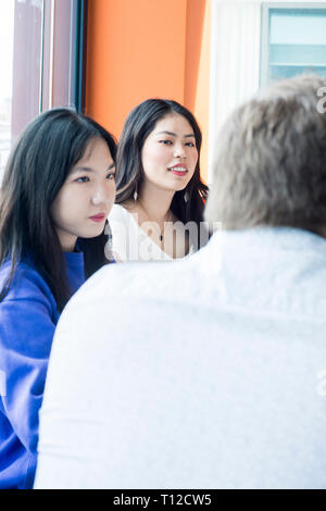 Un sage Western professeur a un tutoriel avec deux étudiants asiatiques dans une salle de classe. Banque D'Images