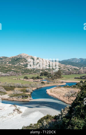 Rivver arrivant à une plage de sable déserte à l'Ostriconi en Balagne Corse sous un ciel bleu clair Banque D'Images