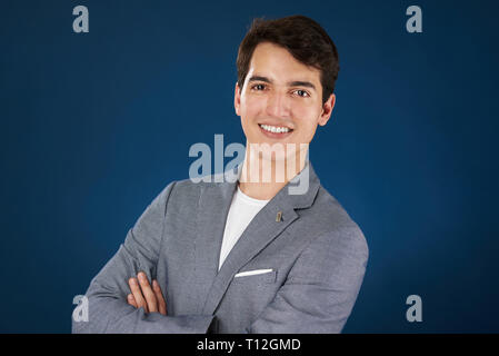 Portrait de jeune homme avec bras croisés isolé sur fond bleu Banque D'Images