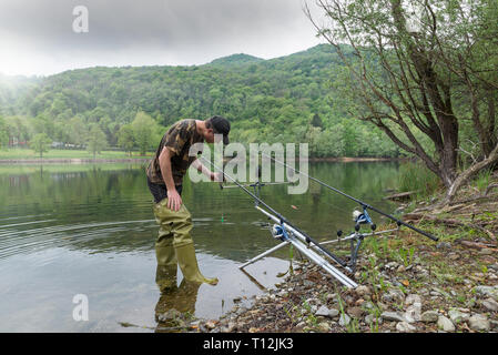Aventures de pêche, pêche à la carpe. Bottes en caoutchouc vert avec pêcheur Banque D'Images