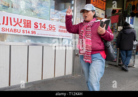 Une femme chinoise religieux tenant une bible promenades sur Main Street dans le quartier chinois en récitant les passages et d'essayer d'engager des étrangers. À Flushing, Queens, NYC Banque D'Images