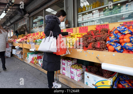 Une jeune femme chinoise pour boutiques fruits & légumes sur un après-midi d'hiver. Dans le quartier chinois, le rinçage, Queens, New York. Banque D'Images