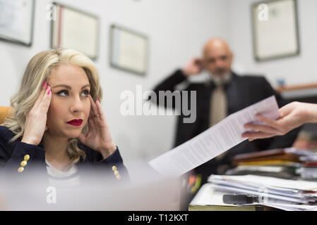 Female office worker a souligné devant une grande charge de travail de bureau et documents