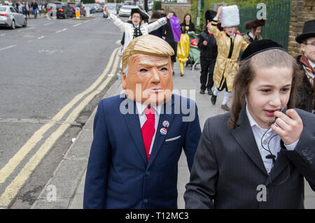 Garçon marchant en masque de Donald Trump et veste de costume pour la fête juive de Pourim à Stamford Hill, Londres 21 mars 2019, Banque D'Images