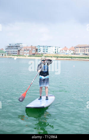 Un mâle en stand up paddle boarder à Hove Lagoon Banque D'Images