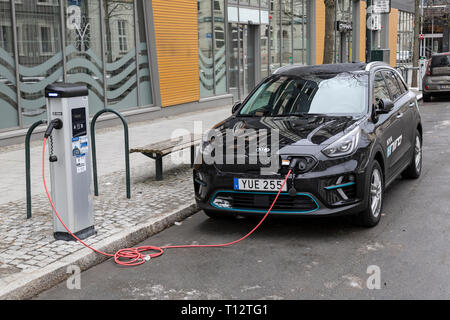 Une Kia Niro Plug In Hybrid car attaché à une station de charge électrique par le côté d'une route dans la ville de Trondheim en Norvège. Banque D'Images