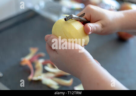 Les mains d'un peeling apple cuisine sur fond gris Banque D'Images