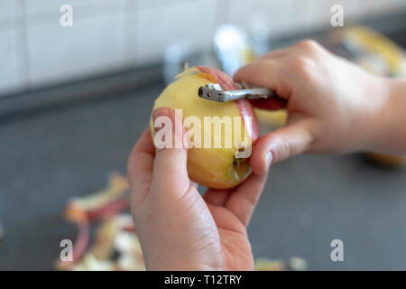 Les mains d'un peeling apple cuisine sur fond gris Banque D'Images