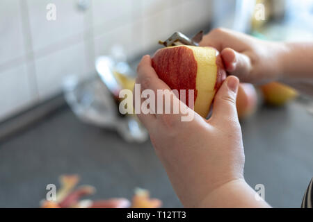 Les mains d'un peeling apple cuisine sur fond gris Banque D'Images