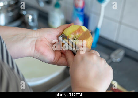 Les mains d'un peeling apple cuisine sur fond gris Banque D'Images