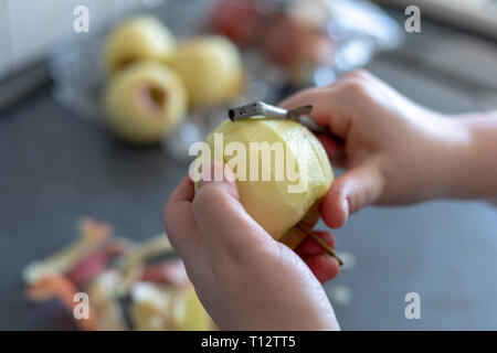 Les mains d'un peeling apple cuisine sur fond gris Banque D'Images