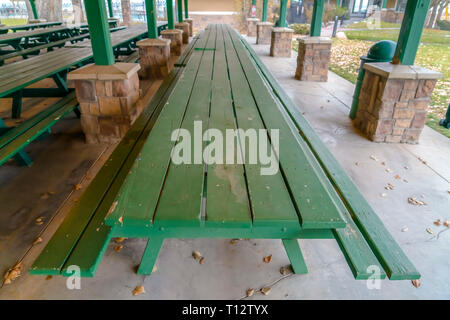 De longues tables en bois et des bancs à l'intérieur d'un pavillon. Close up et la longue table verte en bois avec des bancs à l'intérieur d'un pavillon ouvert. Un vide de l'alimentation publique Banque D'Images