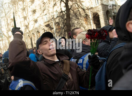 Un manifestant vu jeter des bouquets de fleurs en plastique sur les policiers en tenue de combat à l'extérieur de l'Administration présidentielle, pendant la manifestation. Les manifestants se sont réunis à la place puis ont défilé jusqu'au bâtiment de l'Administration présidentielle d'appeler Président Petro Poroshenko à apporter à la justice les responsables gouvernementaux corrompus. Avec les élections présidentielles en Ukraine qui se tiendra à la fin de mars, les tensions politiques sont très élevés. Banque D'Images