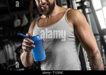 Culturisme. Homme barbu debout à sport avec bouteille close-up smiling happy Banque D'Images