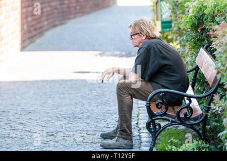 Varsovie, Pologne - 22 août 2018 : la vieille ville avec les homme assis sur le banc de la rue au cours de journée d'été libre de cobblestone cigarette sur le trottoir Banque D'Images