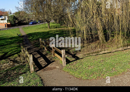 Garde-corps en bois avec un pont sur le ruisseau grâce à Northolt village, saules pleureurs en hiver Banque D'Images