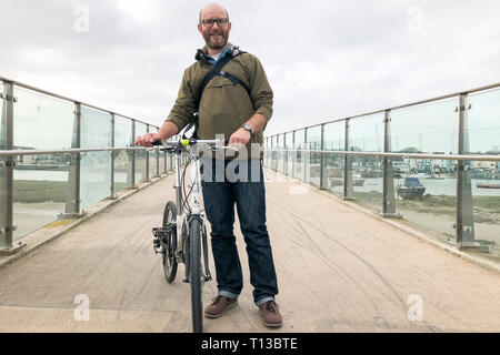 Un homme blanc se dresse sur l'Adur Shoreham Ferry Bridge avec un vélo pliant Banque D'Images