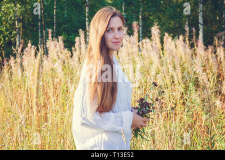 Le portrait de la jeune fille avec un bouquet de fleurs sauvages dans le domaine Banque D'Images