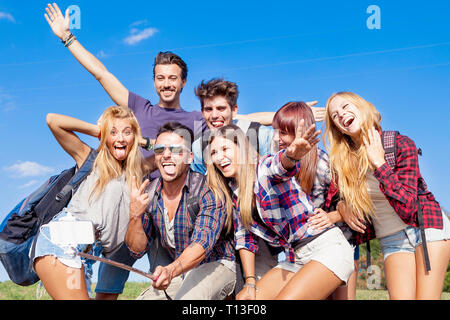 Groupe d'amis de prendre un autoportrait avec stick selfies outdoor Banque D'Images