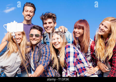 Groupe d'amis de prendre un autoportrait avec stick selfies outdoor Banque D'Images