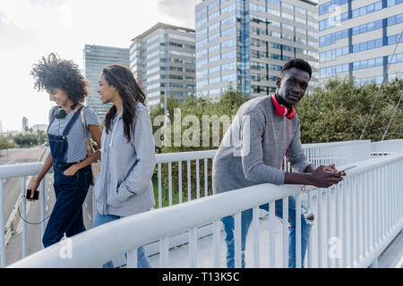 Jeune homme avec un casque debout sur le pont, à l'aide de smartphone, jeunes en marche Banque D'Images