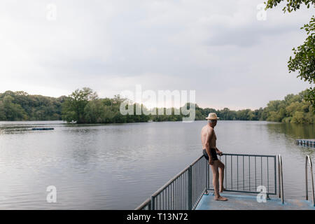 Senior man wearing straw hat standing at a lake Banque D'Images