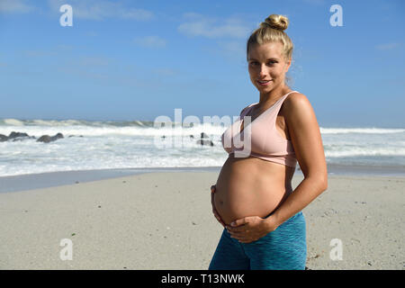 Portrait de femme enceinte active sur la plage Banque D'Images