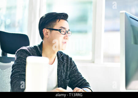 Young Asian business man working in office à l'aide d'ordinateur de bureau. Banque D'Images