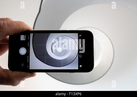 23 mars 2019, la Bavière, Nuremberg : ILLUSTRATION - photographies d'un homme avec un téléphone mobile dans l'escalier de l'escalier en spirale dans le Neues Museum Nürnberg. La liquidation d'escalier noir et blanc moderne, rappelant une coquille d'escargot, est un motif particulièrement populaire pour le réseau social Instagram. Avec d'innombrables images et vidéos de beaux endroits dans le monde, Instagram est l'un des plus populaires des réseaux sociaux. Certains endroits bénéficient de l'attention qu'ils y arrivent, d'autres souffrent et veulent tirer le cordon. (Dpa-Korr : 'Malédiction ou bénédiction ? Comment Bavaria traite de l'Instagram pilgri Banque D'Images