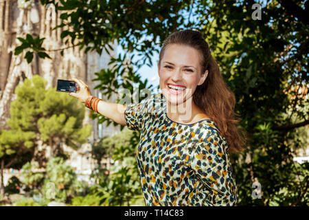 - Barcelone, 06 août 2015 : femme élégante avec de longs cheveux de brunette en jeans et un chemisier en prenant des photos avec un appareil photo numérique à Barcelone, Espagne. Banque D'Images