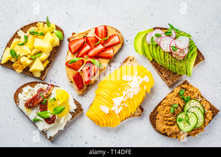 Différents types de sandwichs à la mangue, fraise, tofu pate, avocat, pommes de terre et de la ricotta sur un fond blanc. Banque D'Images