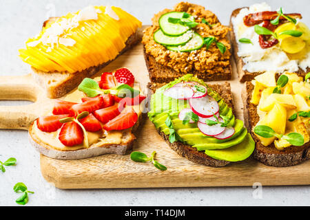 Différents types de sandwichs à la mangue, fraise, tofu pate, avocat, pommes de terre et de la ricotta sur un fond blanc. Banque D'Images