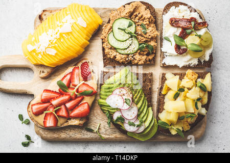 Différents types de sandwichs à la mangue, fraise, tofu pate, avocat, pommes de terre et de la ricotta sur un fond blanc. Banque D'Images