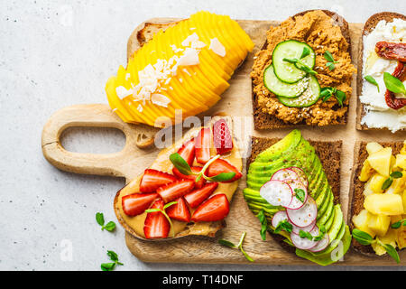 Différents types de sandwichs à la mangue, fraise, tofu pate, avocat, pommes de terre et de la ricotta sur un fond blanc. Banque D'Images