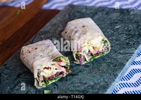 Wraps végétariens de betterave, chou rouge, roquette et humus servi sur la surface en marbre vert Banque D'Images
