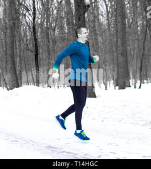 Sporty man jumping ou d'exécution en forêt d'hiver Banque D'Images