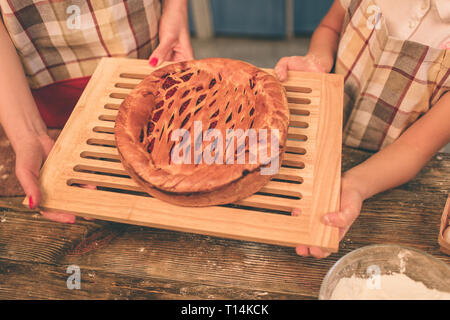 Heureux famille aimante préparent ensemble la boulangerie. Mère et enfant fille girl s'amuser dans la cuisine. Tenant fièrement à la maison fraîchement sorti du pi Banque D'Images