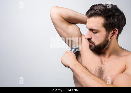 Close up of a guy que le rasage des cheveux sous son aisselle. Il essaie de faire de son mieux. Concept de publicité. Couper la vue. Isolé sur fond blanc Banque D'Images