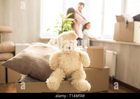 Jolie photo de l'ours de jouet blanc assis sur le fort avec des oreillers. Il est à la droite. Il y a aussi une famille dans la chambre. Ils sont à la recherche Banque D'Images