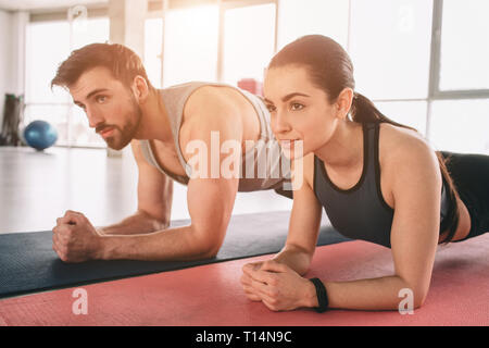 Une photo d'un angle différent où deux belles personnes sont wokring dehors et à l'aide d'une planche position pour cela. Les deux d'entre eux sont à la recherche tout droit Banque D'Images