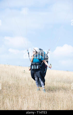 Une jeune femme para planeur décolle de la South Downs. Banque D'Images